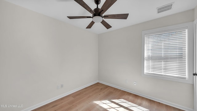 spare room featuring light wood-style floors, baseboards, visible vents, and ceiling fan