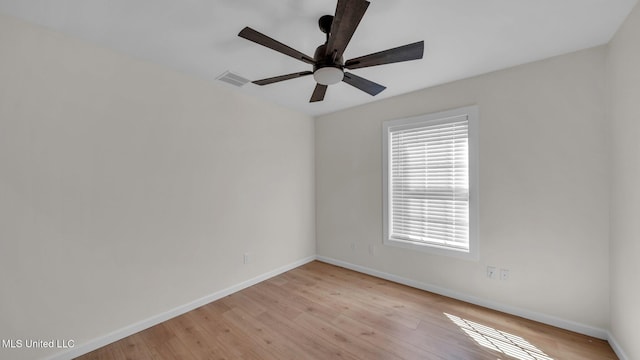 empty room featuring baseboards, visible vents, and light wood finished floors