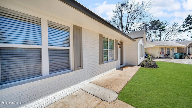 entrance to property featuring brick siding and a yard