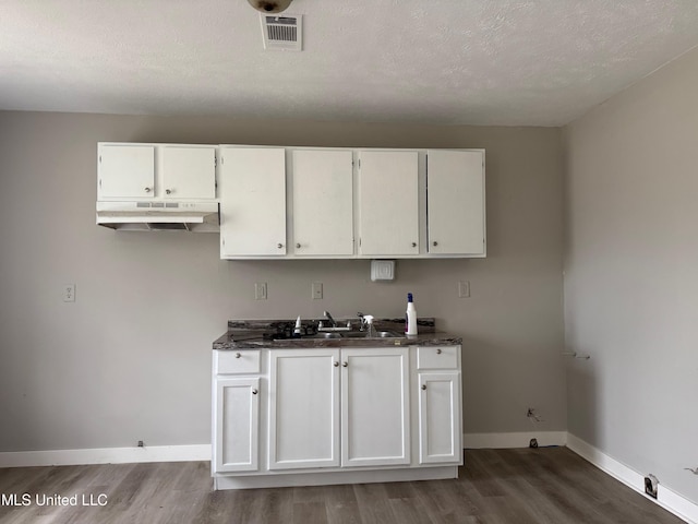 kitchen with white cabinetry, sink, hardwood / wood-style floors, and a textured ceiling