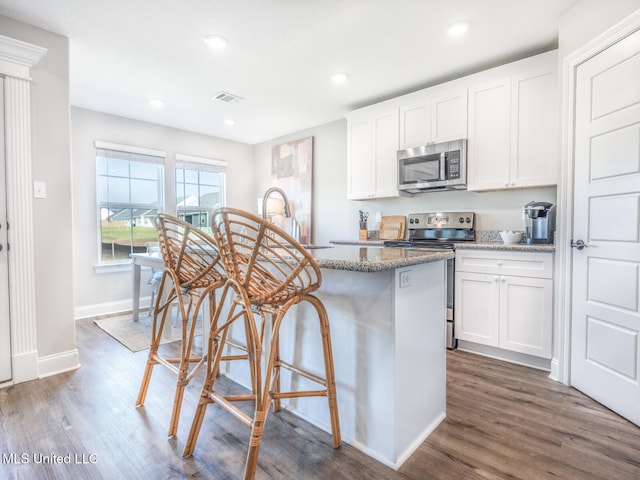 kitchen with light stone countertops, appliances with stainless steel finishes, white cabinets, and a sink