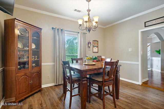 dining room with a notable chandelier, dark hardwood / wood-style flooring, and ornamental molding