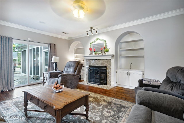 living room featuring ceiling fan, wood-type flooring, built in features, and crown molding