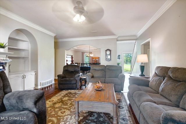 living room featuring ceiling fan with notable chandelier, dark wood-type flooring, and crown molding