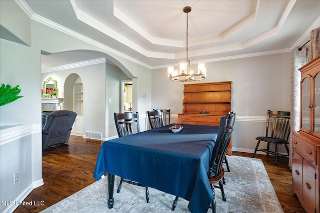 dining room with dark wood-type flooring, crown molding, a tray ceiling, and an inviting chandelier