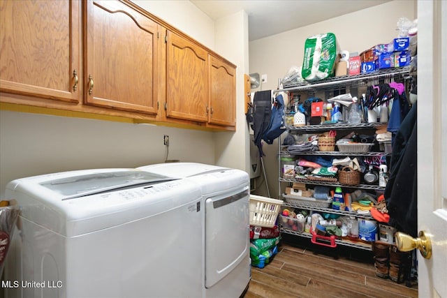 laundry room featuring washing machine and clothes dryer, cabinets, and dark hardwood / wood-style flooring