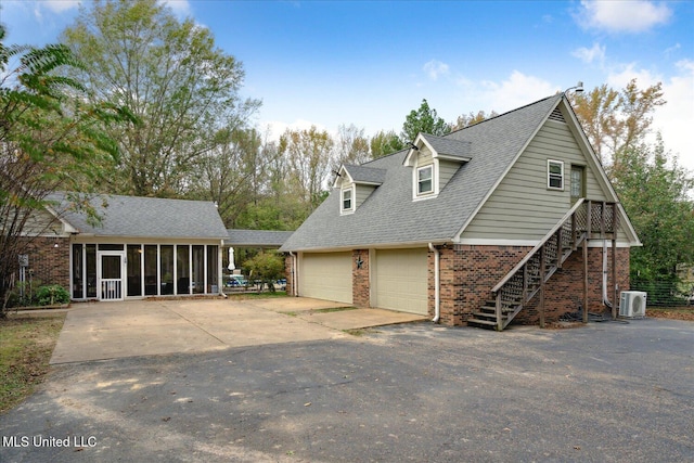 view of front of home featuring a garage, central AC, and a sunroom