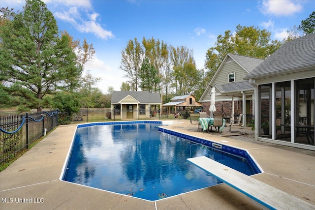 view of swimming pool featuring a diving board and a patio area