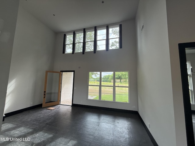 unfurnished living room with a high ceiling and baseboards