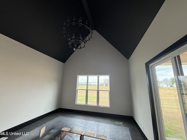empty room featuring a chandelier, baseboards, and high vaulted ceiling