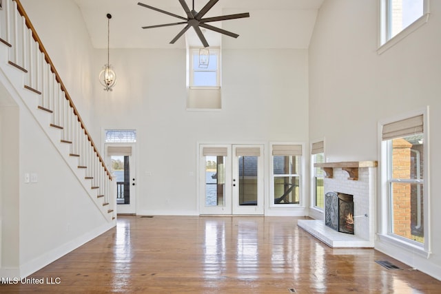 unfurnished living room featuring a high ceiling, ceiling fan with notable chandelier, and a healthy amount of sunlight