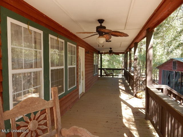 wooden terrace featuring covered porch and ceiling fan