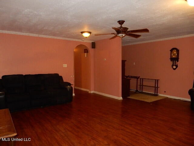 living room with dark wood-type flooring, crown molding, a textured ceiling, and ceiling fan