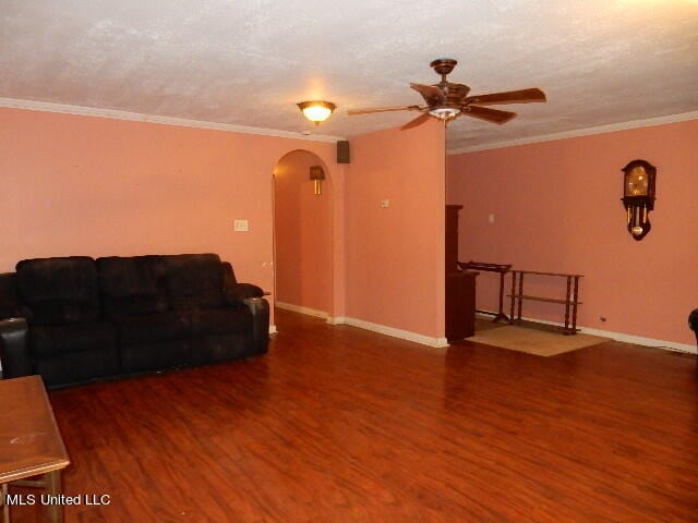 living room with ornamental molding, dark wood-type flooring, a textured ceiling, and ceiling fan