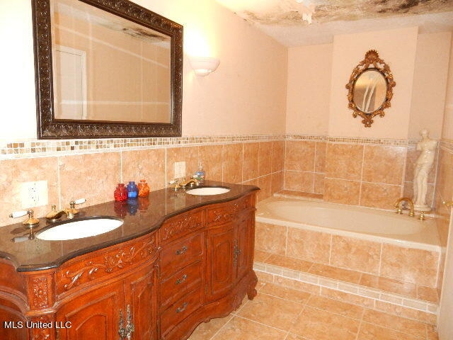 bathroom featuring vanity, a relaxing tiled tub, and tile patterned floors