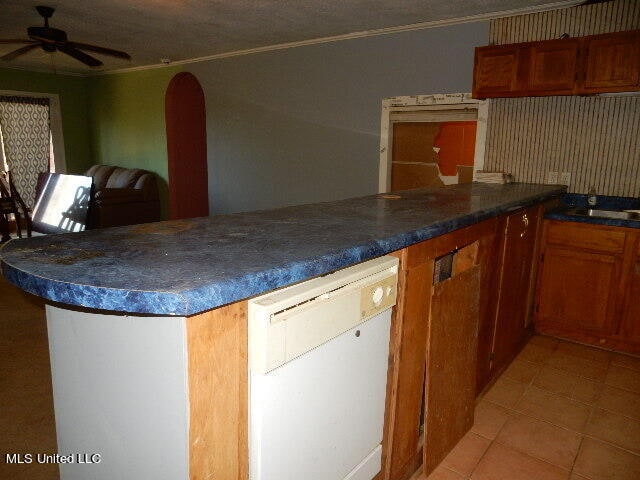 kitchen featuring dishwasher, kitchen peninsula, ceiling fan, crown molding, and light tile patterned floors