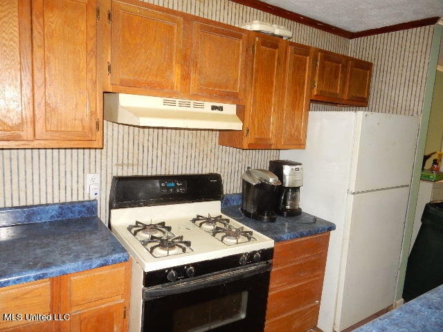 kitchen with ornamental molding and white appliances