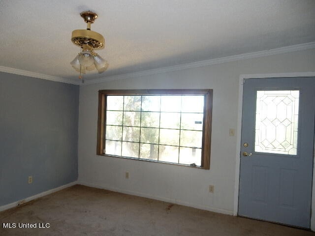 foyer entrance featuring ceiling fan, lofted ceiling, carpet flooring, and ornamental molding