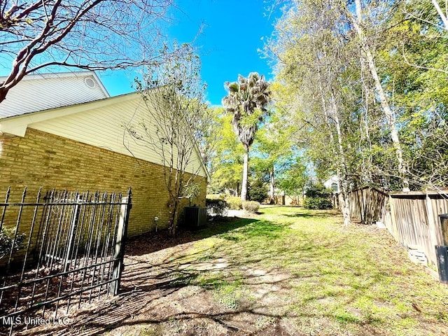 view of yard with central air condition unit and fence