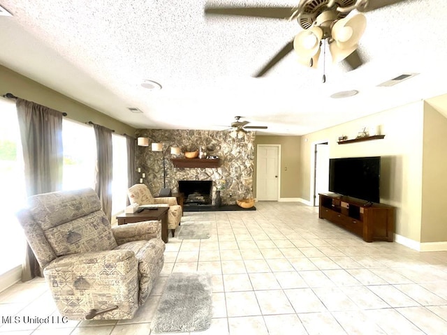 living area featuring baseboards, a textured ceiling, ceiling fan, and light tile patterned flooring