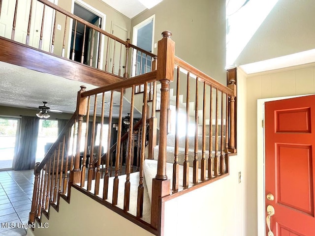 staircase featuring tile patterned flooring and ceiling fan