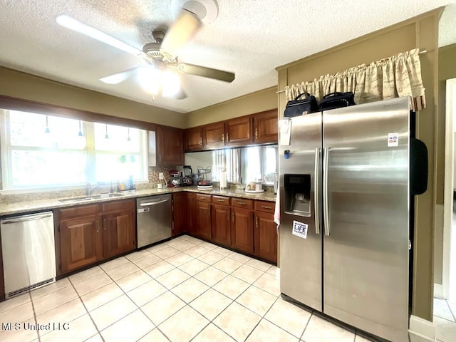 kitchen with appliances with stainless steel finishes, a sink, a textured ceiling, a ceiling fan, and light tile patterned floors