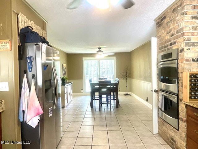 kitchen featuring appliances with stainless steel finishes, a textured ceiling, ceiling fan, and light tile patterned floors