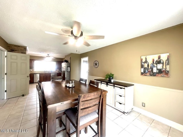 dining area featuring a textured ceiling, ceiling fan, and light tile patterned floors