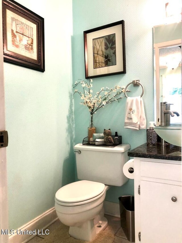 half bath featuring toilet, baseboards, tile patterned flooring, and vanity