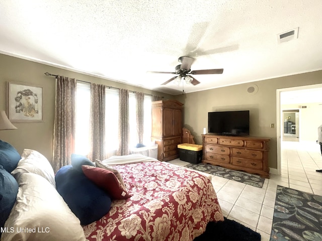bedroom featuring crown molding, ceiling fan, a textured ceiling, light tile patterned floors, and visible vents