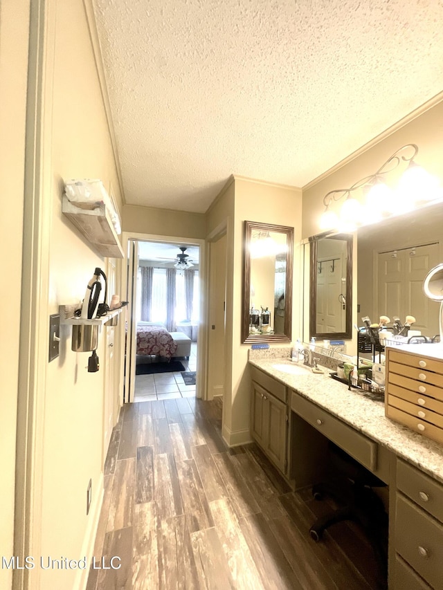 ensuite bathroom with vanity, wood finished floors, connected bathroom, a textured ceiling, and a ceiling fan