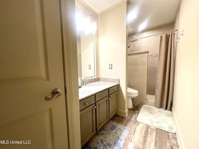 full bath with toilet, a tile shower, wood finished floors, and vanity