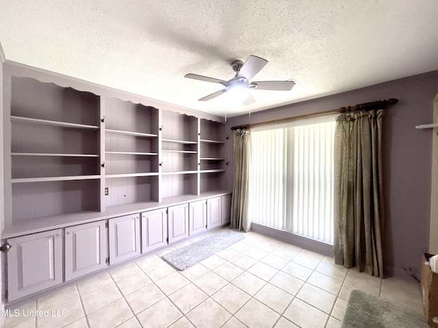 empty room with light tile patterned floors, a ceiling fan, and a textured ceiling
