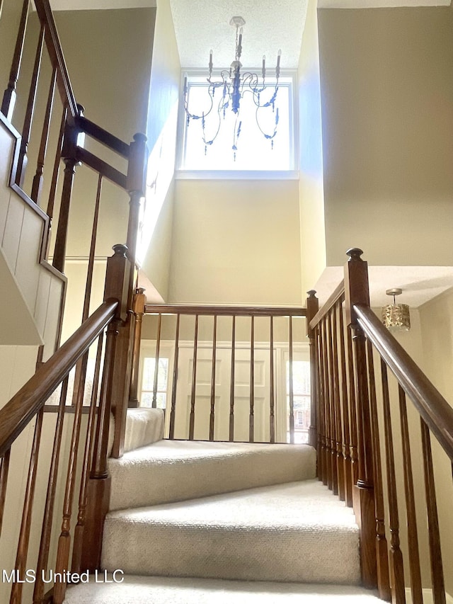 staircase featuring an inviting chandelier and a towering ceiling