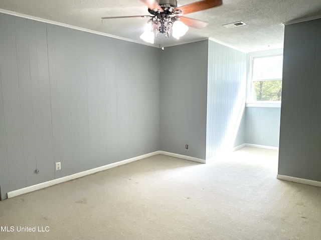 carpeted empty room featuring crown molding, ceiling fan, visible vents, and baseboards