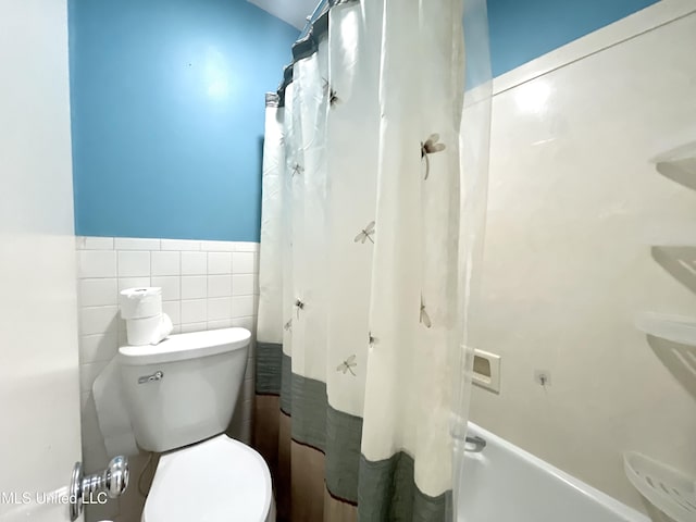 bathroom featuring tile walls, wainscoting, and toilet