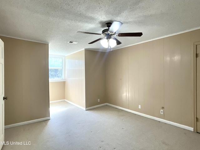 carpeted empty room featuring visible vents, a textured ceiling, ceiling fan, and baseboards