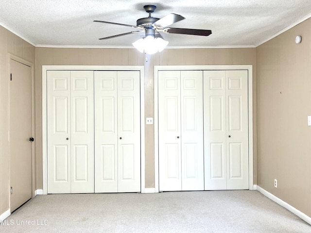 unfurnished bedroom featuring two closets, crown molding, and light carpet