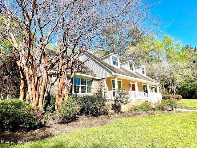 view of front of property featuring a porch, brick siding, and a front yard