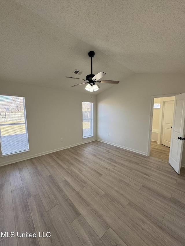 spare room featuring baseboards, vaulted ceiling, wood finished floors, a textured ceiling, and a ceiling fan