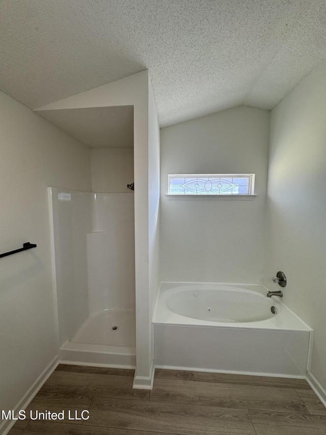 full bath with wood finished floors, lofted ceiling, a shower, a textured ceiling, and a garden tub