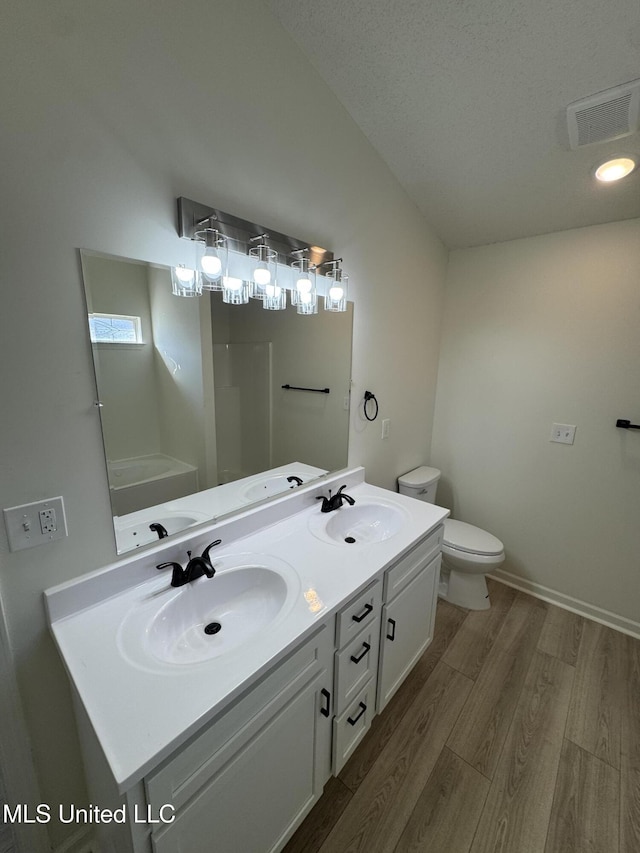 bathroom featuring a sink, visible vents, wood finished floors, and double vanity