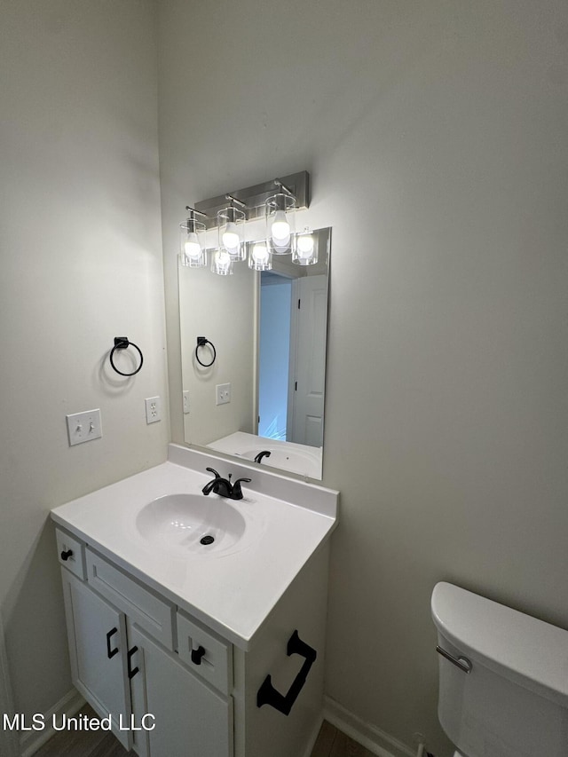 bathroom featuring vanity, toilet, and baseboards