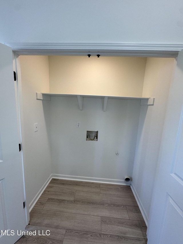 clothes washing area featuring laundry area, wood finished floors, baseboards, and washer hookup