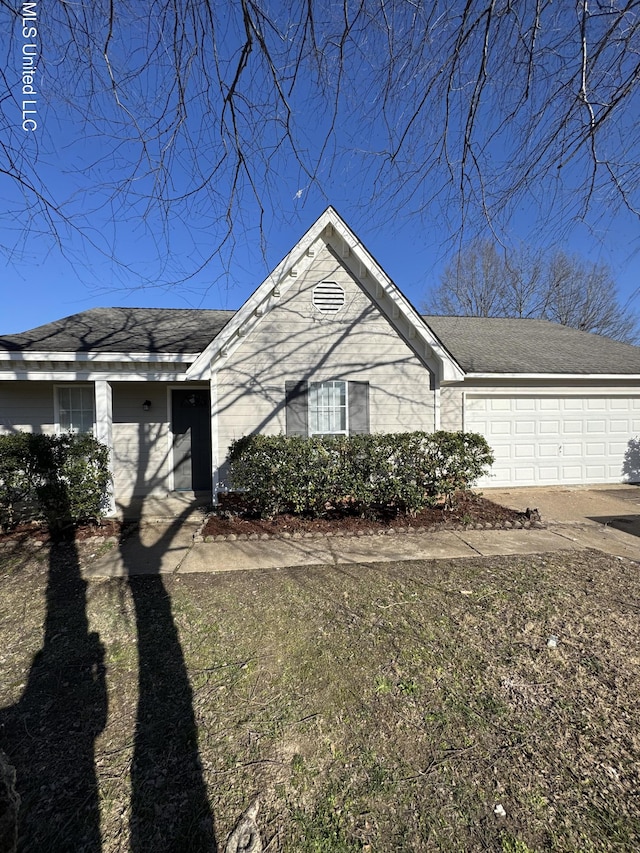 view of front of home with driveway, a garage, and roof with shingles