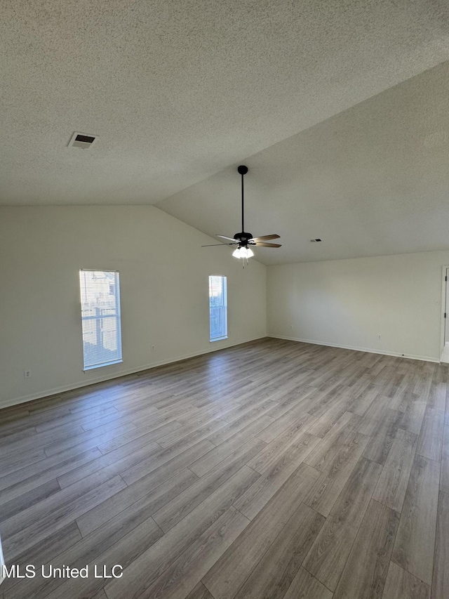 unfurnished room featuring ceiling fan, lofted ceiling, a textured ceiling, and wood finished floors