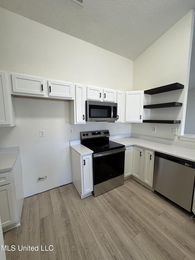 kitchen featuring open shelves, light countertops, light wood-style floors, appliances with stainless steel finishes, and white cabinetry