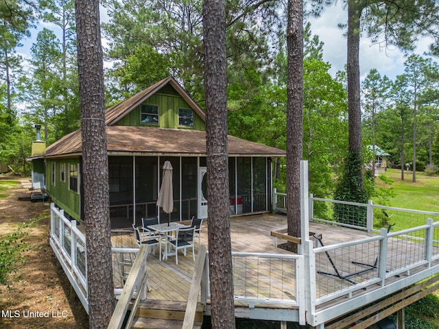 146 Maple Dr, Perkinston, MS 39573 - rear view of property featuring a sunroom, a wooden deck, outdoor dining area, and view of scattered trees