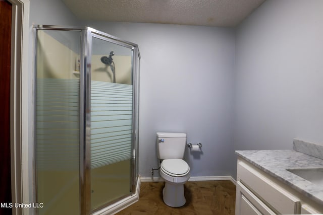 bathroom featuring a shower with door, vanity, a textured ceiling, and toilet