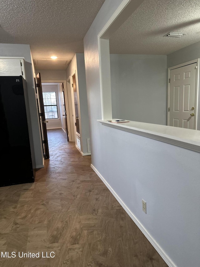 corridor with dark parquet floors and a textured ceiling